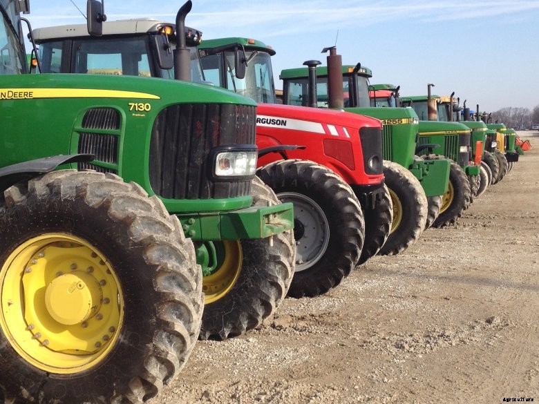 Green and red tractors lined up at auction